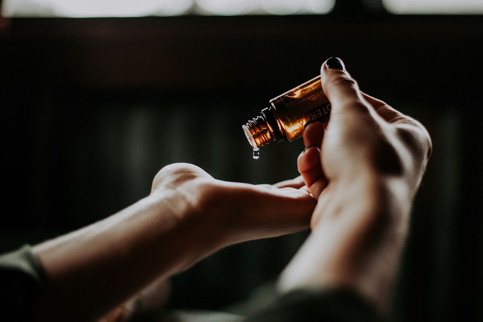 Peau sèche : ces huiles essentielles qui réinventent votre routine beauté 2 person holding amber glass bottle