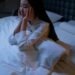 Woman in White Long Sleeve Shirt Sitting on a Bed