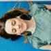 Young woman meditating with closed eyes on a yoga mat, listening to music.