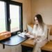 Woman reading magazine in a cozy tiny house with a scenic view.