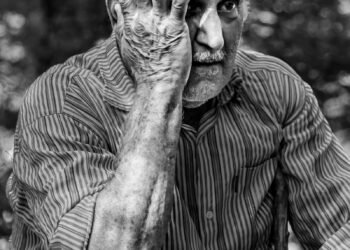 man in pinstriped long-sleeved shirt putting hand on face