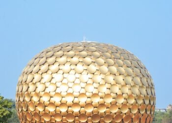 a large golden ball sitting on top of a lush green field