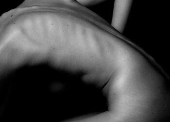 a naked woman sitting on a table with her back to the camera