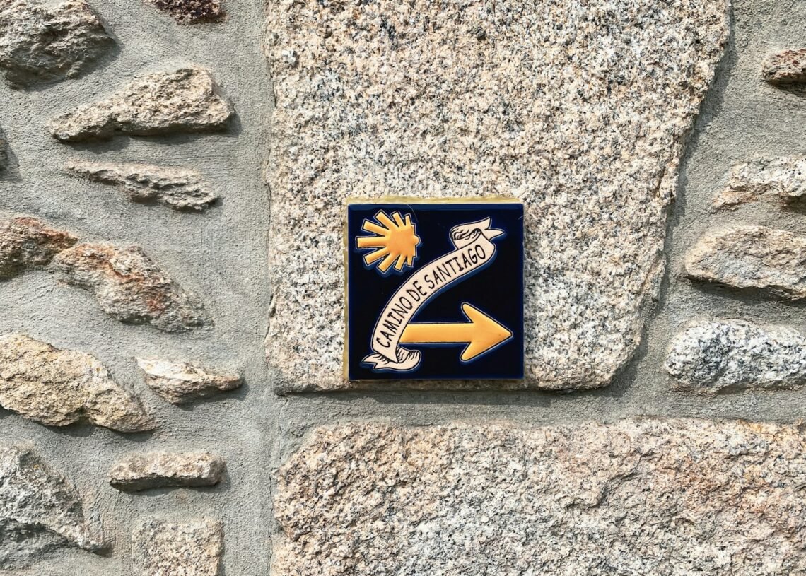 Le Chemin de Compostelle : Itinéraires, Histoire et Conseils Pratiques 1 a sign on a stone wall pointing to the right