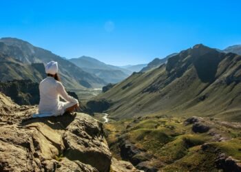 a person sitting on a rock looking out over a valley