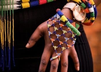 person holding beaded blue and yellow necklace
