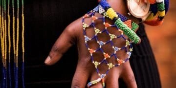 person holding beaded blue and yellow necklace