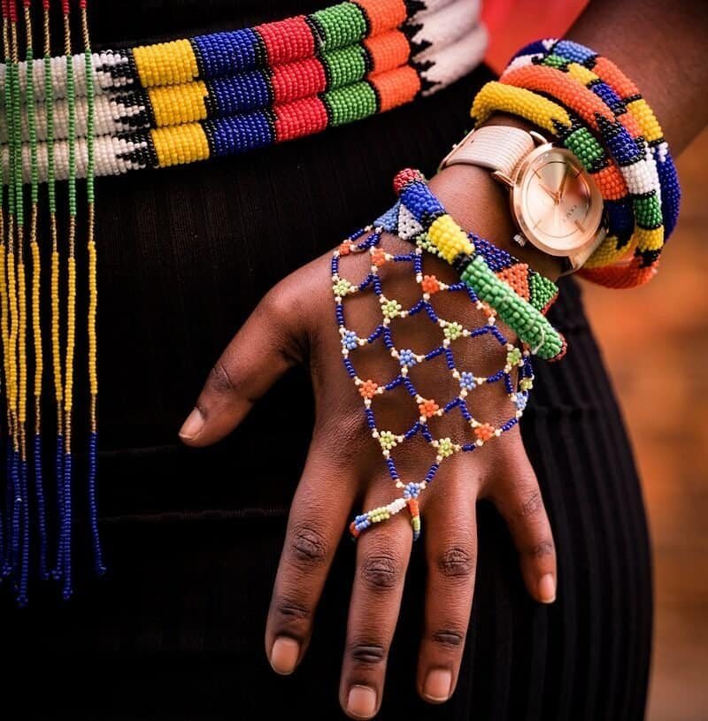 person holding beaded blue and yellow necklace
