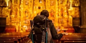 Les vacances ne servent à rien. Le pèlerinage change tout. 4 Pilgrim with backpack facing ornate church altar