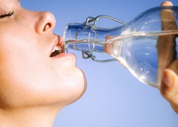 Femme buvant de l'eau fraîche en plein été, symbole d'hydratation et de fraîcheur pendant la canicule