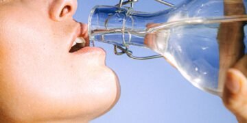 Comment rester au frais en canicule 3 Femme buvant de l'eau fraîche en plein été, symbole d'hydratation et de fraîcheur pendant la canicule