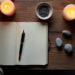 Rituel de nouvelle lune : guide et limites 7 Carnet ouvert, stylo et bougies allumees sur une table en bois, rituel de nouvelle lune