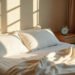 Lit défait avec plaid en lin et réveil sur la table de nuit, lumière d'après-midi filtrée par les volets, sieste